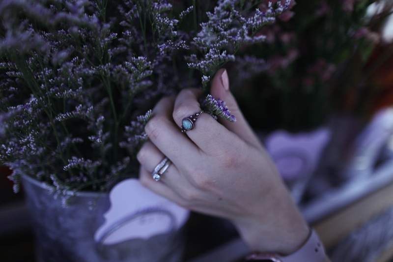 Woman wearing stacked rings arranges flowers